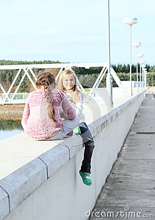 Girls sitting on railing of dam Stock Photo