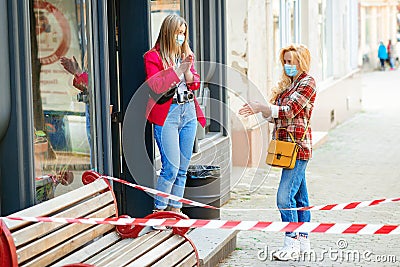 Girls take coffee to go in modern coffee shop outdoors. Coronavirus quarantine. Women in medical masks Stock Photo