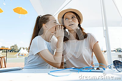 Girls teenagers having fun, talk, secret, laugh. Sit in a street cafe, sunny summer day in recreation and entertainment area, yout Stock Photo