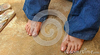 Dirty girl`s feet resting with flip-flops next to her after working in the garden. Stock Photo