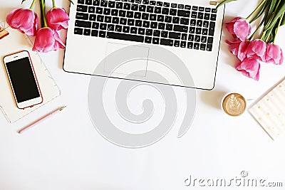 Top view of female worker desktop with laptop, flowers and different office supplies items. Feminine creative design workspace. Stock Photo