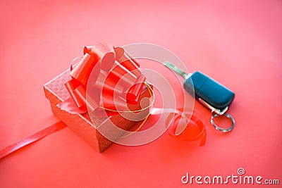 Give gift car key concept Red gift box with red ribbon bow and key car as present on red background Stock Photo