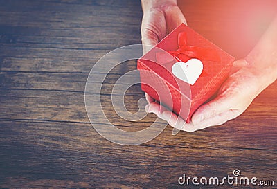 Give Love Man holding small red present box in hands with Heart for love Valentines day Giving a gift box with red ribbon Stock Photo