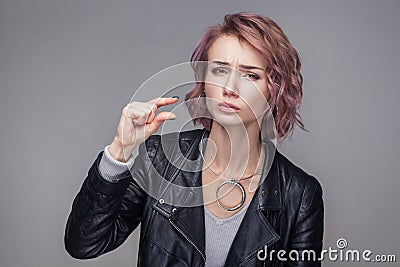 Give me a little bit. Portrait of hopeful beautiful girl with short hair and makeup in casual style black leather jacket standing Stock Photo