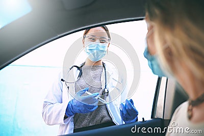 Give safety your best shot. a masked young doctor giving a patient an injection at a Covid-19 drive through testing Stock Photo