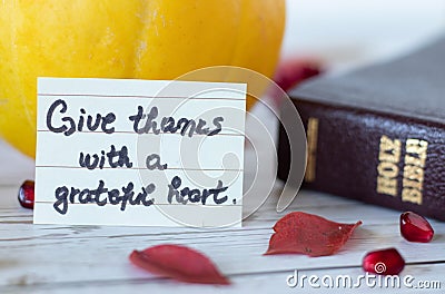 Give thanks with a grateful heart, a handwritten quote with Holy Bible Book and pumpkin. Stock Photo