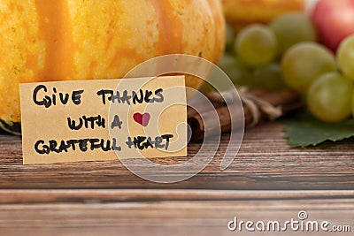 Give thanks with a grateful heart, a handwritten text on a vintage card with various autumn fruit in the background Stock Photo