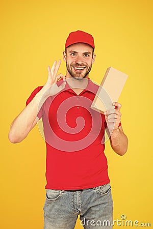 Giving perfect service. Courier delivery. Postman worker. Man red cap yellow background. Transportation agency Stock Photo