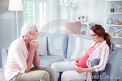 Loving grey-haired mother giving some advice to pregnant daughter Stock Photo