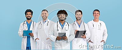 Glad adult, senior caucasian, indian, arab doctors in white coats with tablets work in clinic Stock Photo