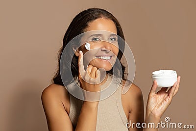 Glad caucasian senior lady show jar of cream, enjoy beauty care, anti-wrinkle treatment Stock Photo