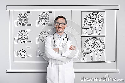 Glad doctor folding his hands and standing against the wall. Stock Photo