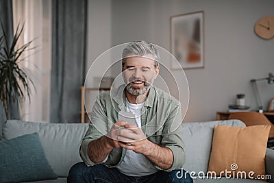 Glad elderly european man with beard chatting on smartphone, watching video, playing game Stock Photo