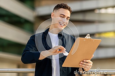 Glad handsome millennial caucasian man engineer businessman, enjoy work with clipboard Stock Photo