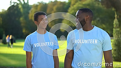 Glad male volunteers smiling to each other, eco project participation, help Stock Photo