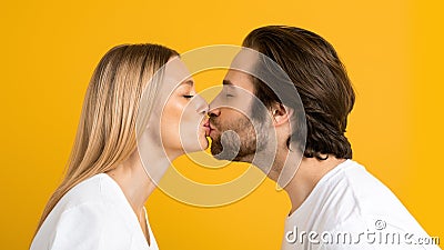 Glad millennial european guy and woman in white t-shirts kiss and enjoy tender moment together Stock Photo