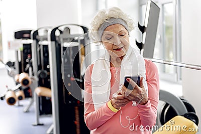 Glad retiree looking at mobile in gym Stock Photo