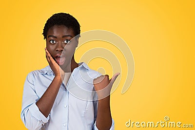 Glad shocked teen black lady student in casual with open mouth, point finger at empty space Stock Photo