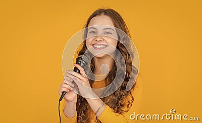 glad teen kid with microphone on yellow background Stock Photo