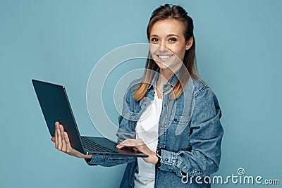 Gladful young woman in jeans shirt using computer or laptop over blue background. Stock Photo