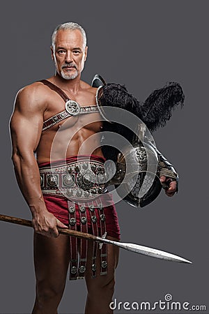 Gladiator in lightweight historical armor against grey studio background Stock Photo