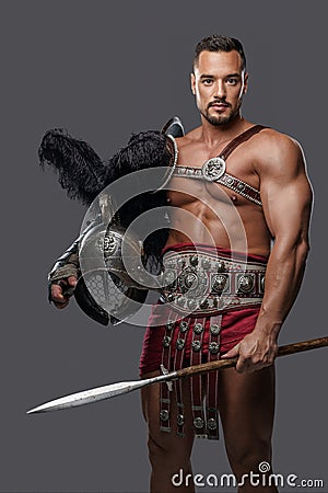 Gladiator in lightweight historical armor against grey studio background Stock Photo
