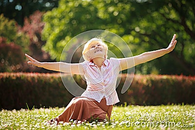 Gladness. Meditation. Mature Pleased Woman Relaxing with Outspread Arms Stock Photo