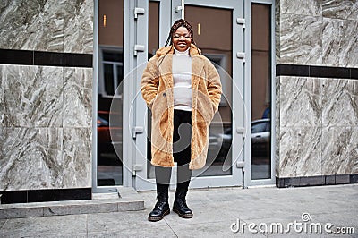 Glamorous african american woman in warm fur coat, eyeglasses pose at street Stock Photo