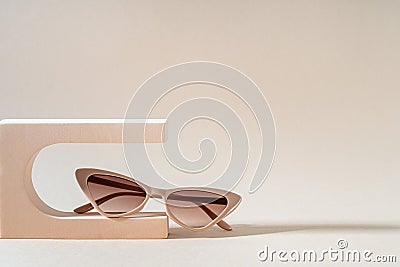 Glamour cat eye frame sunglasses on a podium on a beige background. Women's Trendy sunglasses still life in minimal stile. Stock Photo