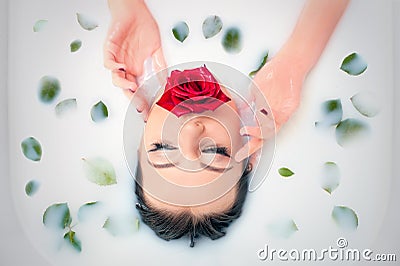 Glamour closeup portrait in milk bath with and leaves rose petals. Stock Photo