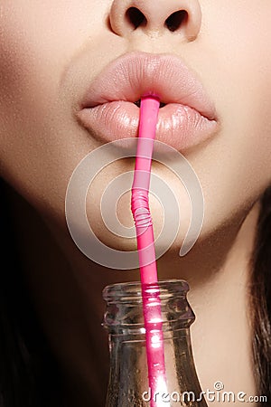 Glamour closeup of woman`s lips drinking with pink straw. Natural makeup. Fashion summer look with bottle of water Stock Photo