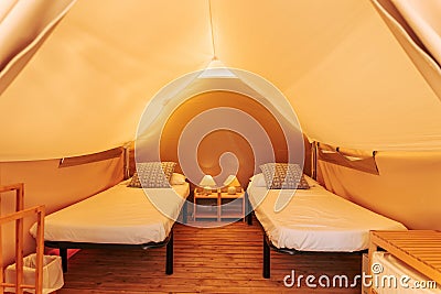 Glamping tent cozy interior with beds on a sunny day. Glamorous camping tent for outdoor summer holiday and vacation lifestyle Stock Photo