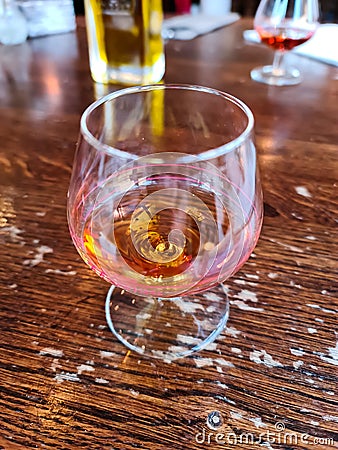 A glass of amaretto with soft background on a wooden table Stock Photo