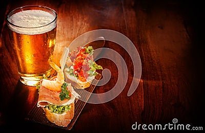 Glass of beer with delicious tapas Stock Photo