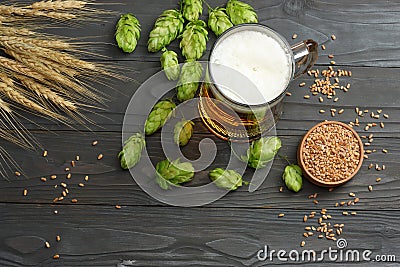 Glass beer with hop cones and wheat ears on dark wooden background. Beer brewery concept. Beer background. top view Stock Photo