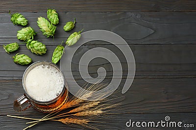 Glass beer with hop cones and wheat ears on dark wooden background. Beer brewery concept. Beer background. top view Stock Photo
