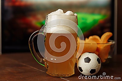 Glass with beer and snack in front of screen with football game. Soccer fans Stock Photo