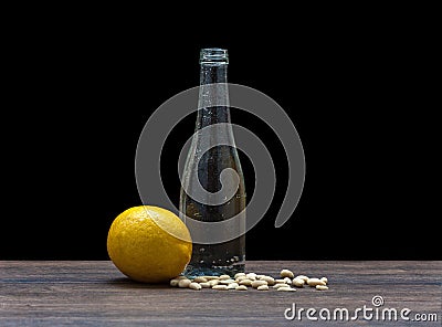 Glass bottle on a black background, peanut and lemon, the shape of the bottle with lemon and peanuts. the theme of Stock Photo