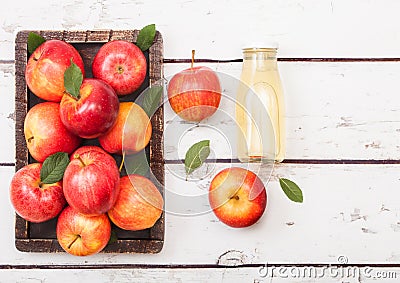 Glass bottle of fresh organic apple juice with pink lady red apples in vintage box on wooden background Stock Photo