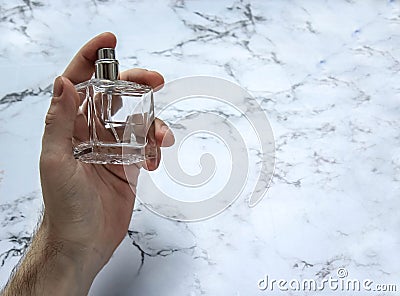 A glass bottle of male perfume in hand Stock Photo