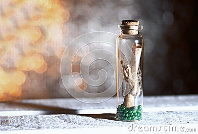 Glass bottle with a note inside. A note in the form of rolled up paper bound in a rope. Beads are poured at the bottom of the Stock Photo