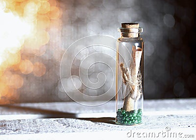 Glass bottle with a note inside. A note in the form of rolled up paper bound in a rope. Beads are poured at the bottom of the Stock Photo