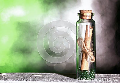 Glass bottle with a note inside. A note in the form of rolled up paper bound in a rope. Beads are poured at the bottom of the Stock Photo
