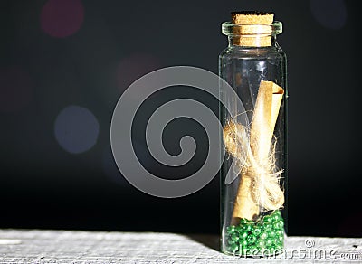 Glass bottle with a note inside. A note in the form of rolled up paper bound in a rope. Beads are poured at the bottom of the Stock Photo