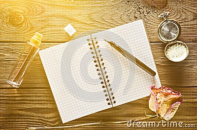 A glass bottle with perfume, notebook and a pen, dry rose Stock Photo