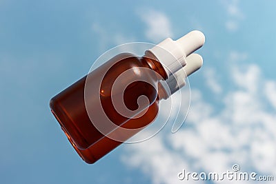 Glass bottle with serum on background of clouds and sky close-up. Stock Photo