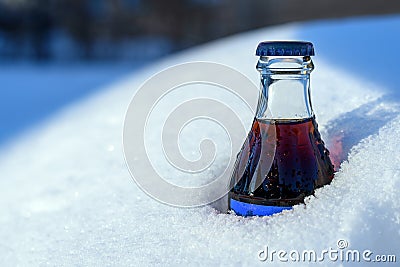 Glass bottle of soda coke stuck in snow snow snow snow in sunset light Stock Photo