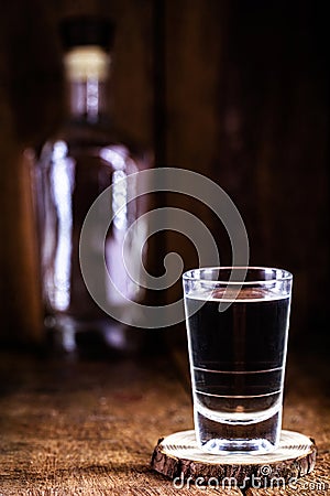 Glass and bottle of strong distilled alcohol, brandy, sugar cane-based drink Stock Photo