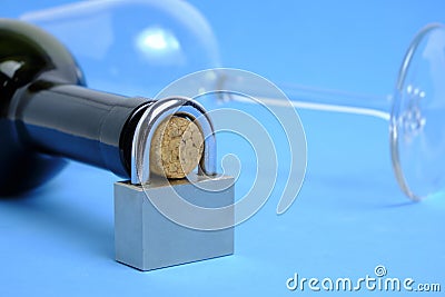 Glass and bottle wine with lock on neck on blue background.Concept ban on drinking, prohibition. Stock Photo