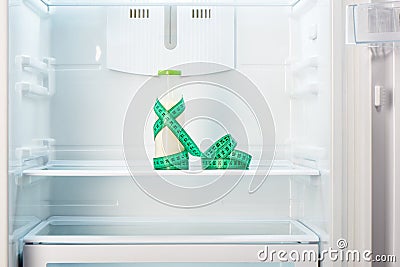 Glass bottle of yoghurt with measuring tape on shelf of open empty refrigerator Stock Photo